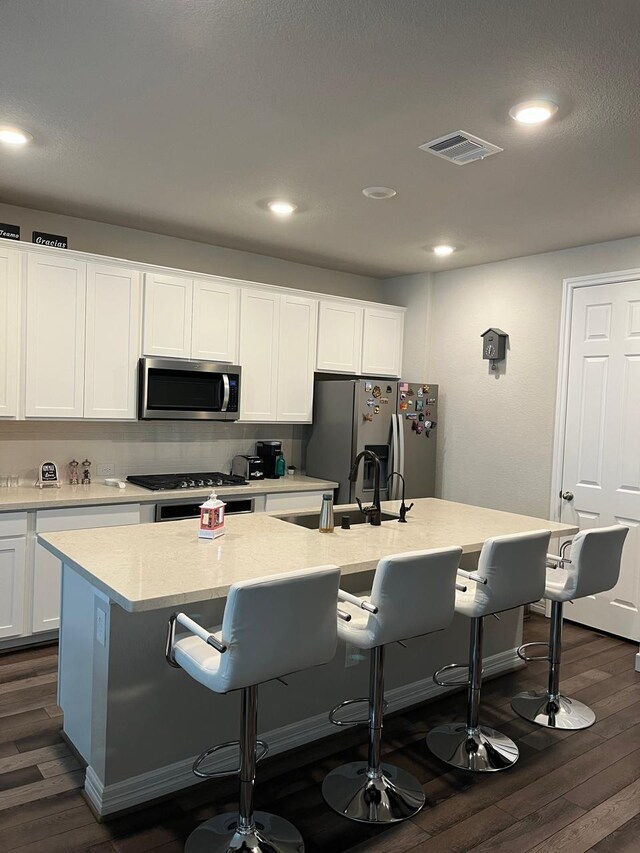 kitchen featuring visible vents, dark wood finished floors, appliances with stainless steel finishes, and a breakfast bar