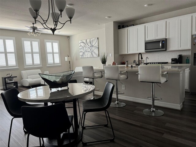 dining area with baseboards, a textured ceiling, a notable chandelier, and dark wood-style floors