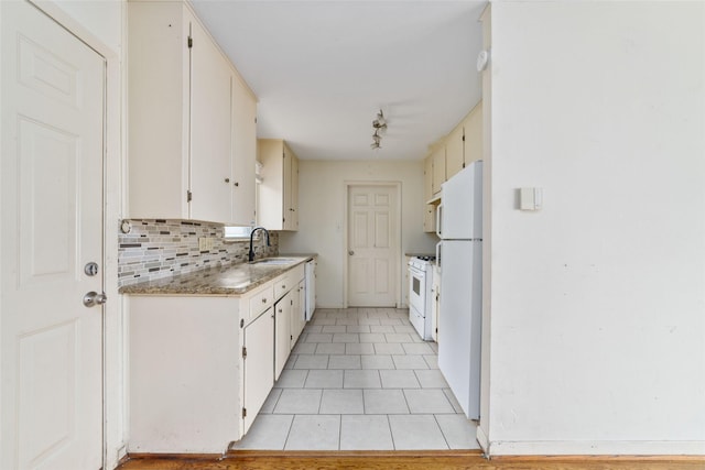 kitchen featuring tasteful backsplash, a sink, light tile patterned floors, white appliances, and white cabinetry