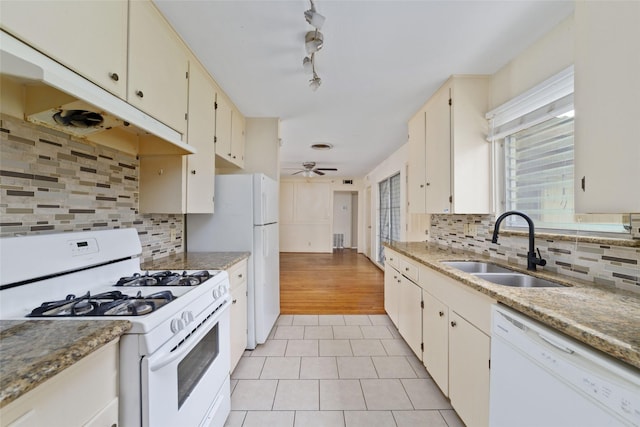 kitchen featuring white appliances, light tile patterned floors, a sink, and tasteful backsplash