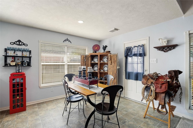 dining space with visible vents, a textured ceiling, and baseboards