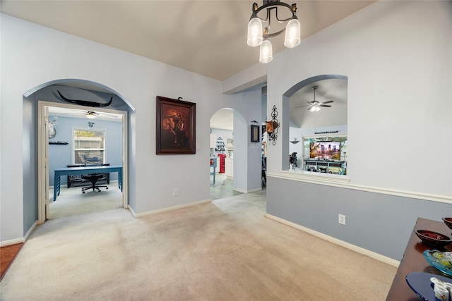 corridor featuring an inviting chandelier, arched walkways, baseboards, and light colored carpet