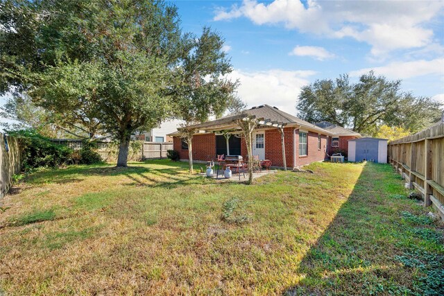 view of yard with a fenced backyard, a patio, an outdoor structure, and a shed