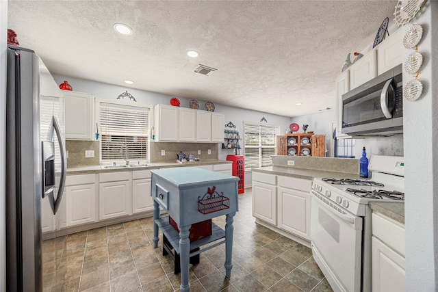 kitchen featuring a textured ceiling, appliances with stainless steel finishes, a sink, and visible vents