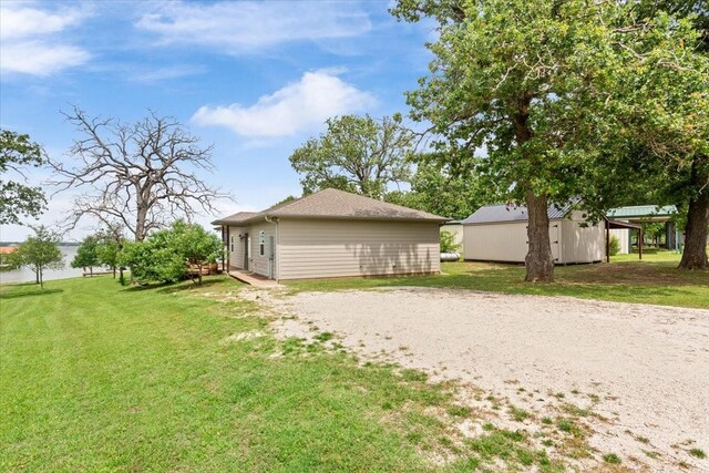 rear view of house with a lawn, an outbuilding, and a water view