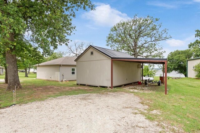 exterior space featuring dirt driveway, a yard, and an attached carport
