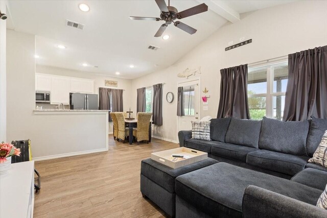 living area with visible vents, lofted ceiling with beams, light wood finished floors, and ceiling fan