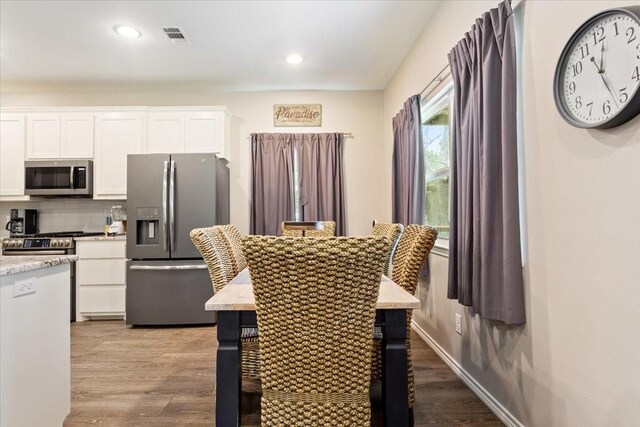 kitchen featuring white cabinetry, wood finished floors, tasteful backsplash, and stainless steel appliances