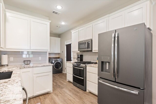 kitchen featuring appliances with stainless steel finishes, decorative backsplash, white cabinetry, and visible vents