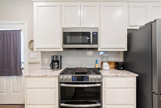 kitchen with decorative backsplash, white cabinetry, light stone countertops, and stainless steel appliances