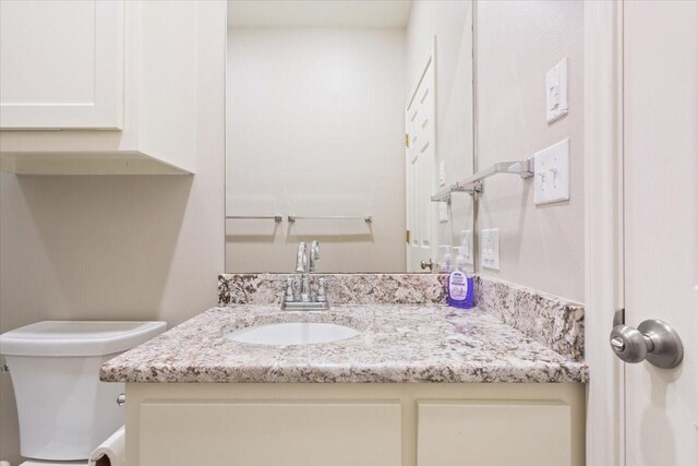 half bathroom featuring vanity and toilet