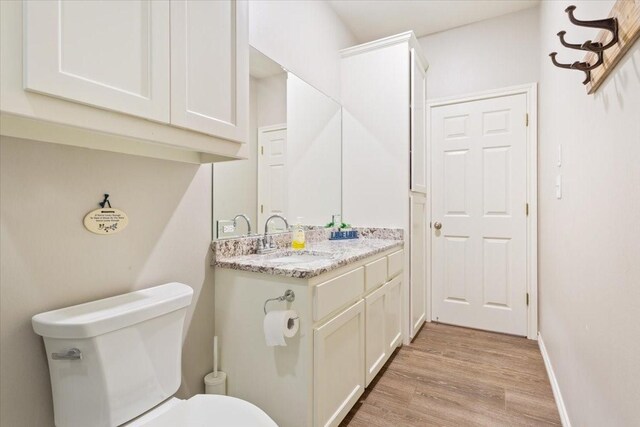 bathroom with toilet, baseboards, wood finished floors, and vanity