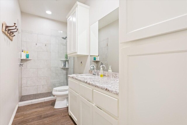 bathroom featuring a walk in shower, vanity, toilet, and wood finished floors