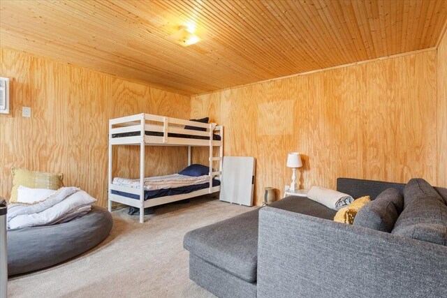 carpeted bedroom featuring wooden walls and wood ceiling