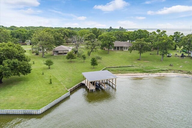dock area with boat lift, a water view, and a yard