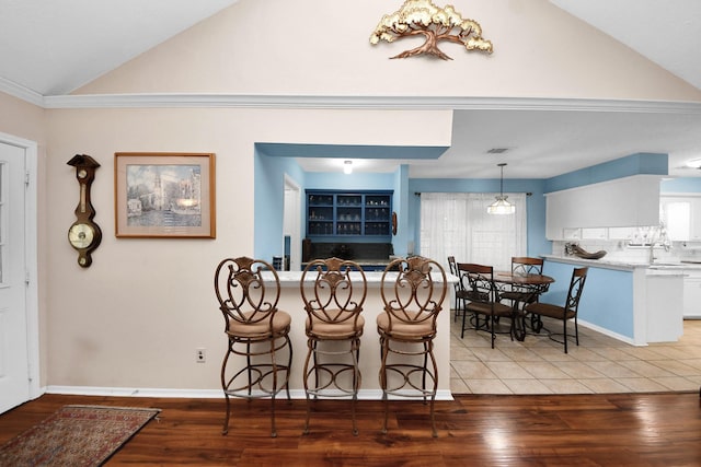 dining space featuring wood finished floors, baseboards, lofted ceiling, and visible vents