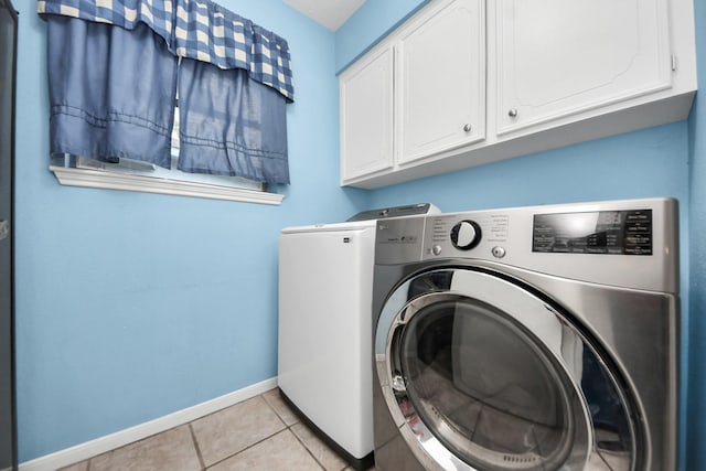 washroom with baseboards, light tile patterned flooring, cabinet space, and washer and dryer