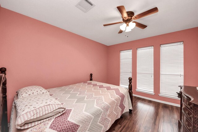 bedroom featuring visible vents, baseboards, ceiling fan, and dark wood-style floors