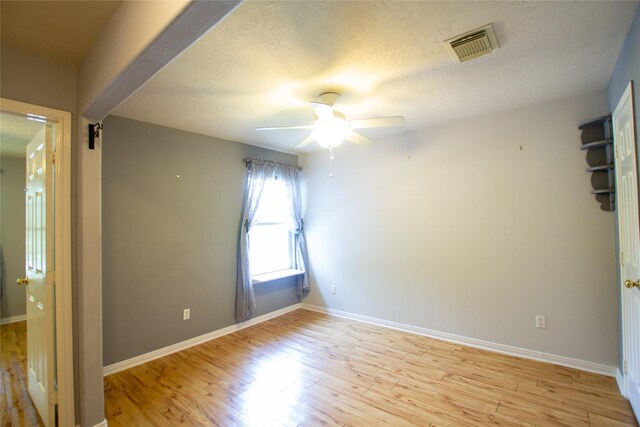 spare room with visible vents, a ceiling fan, light wood finished floors, and baseboards