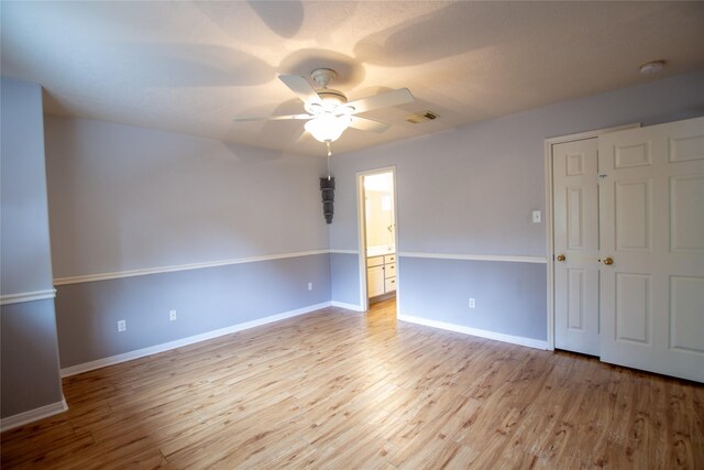 empty room featuring visible vents, a ceiling fan, baseboards, and light wood-type flooring