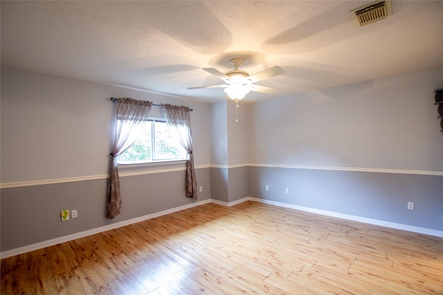 unfurnished room with ceiling fan, visible vents, baseboards, and light wood-type flooring