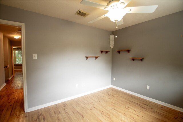empty room featuring baseboards, ceiling fan, light wood-type flooring, and visible vents