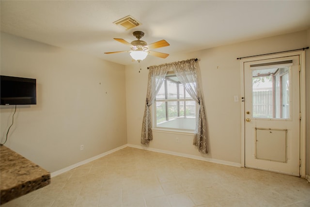 interior space featuring visible vents, baseboards, ceiling fan, and a wealth of natural light