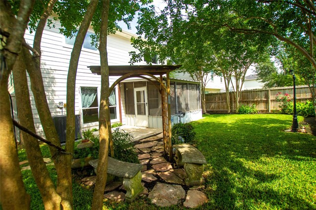 view of yard with fence, central AC unit, and a sunroom