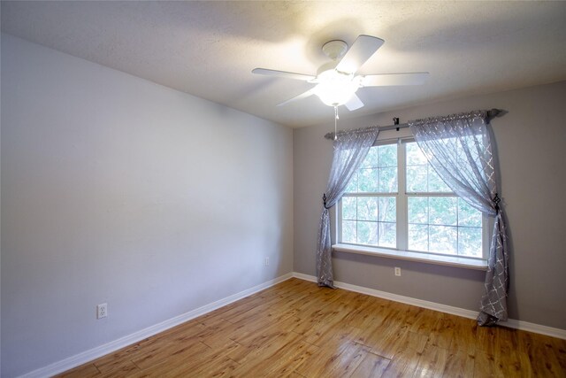 unfurnished room with baseboards, ceiling fan, and light wood-type flooring