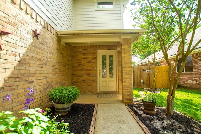 property entrance with brick siding, a gate, and fence