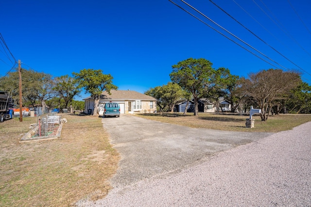 view of front facade with a front yard, a garden, and aphalt driveway