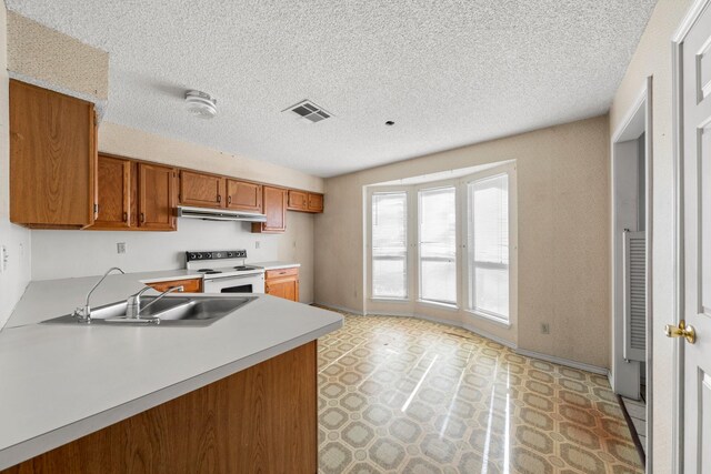 kitchen with visible vents, white electric range, brown cabinets, light countertops, and light floors