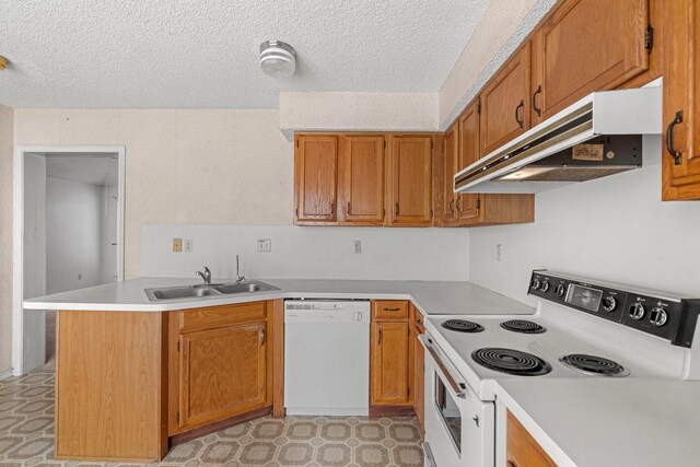 kitchen featuring a sink, light countertops, a peninsula, under cabinet range hood, and white appliances