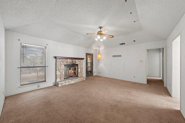 unfurnished living room featuring a ceiling fan, a stone fireplace, a textured ceiling, visible vents, and carpet flooring