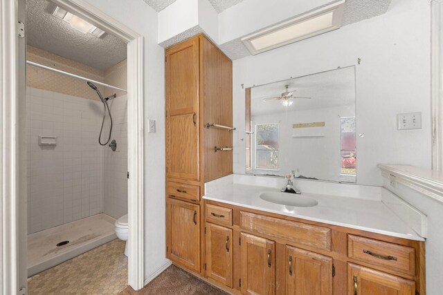 bathroom featuring vanity, a ceiling fan, toilet, and tiled shower