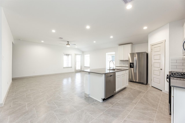 kitchen featuring stainless steel appliances, a ceiling fan, dark countertops, and a sink
