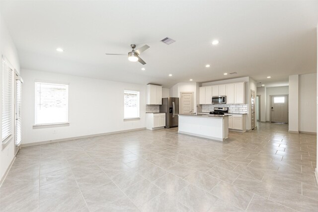 kitchen with visible vents, open floor plan, ceiling fan, appliances with stainless steel finishes, and backsplash