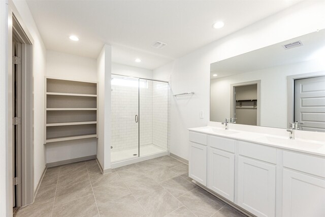 bathroom with visible vents, a sink, a spacious closet, and a shower stall
