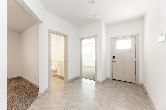 foyer featuring light tile patterned floors, baseboards, and light carpet