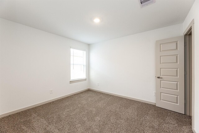 carpeted empty room featuring baseboards and visible vents