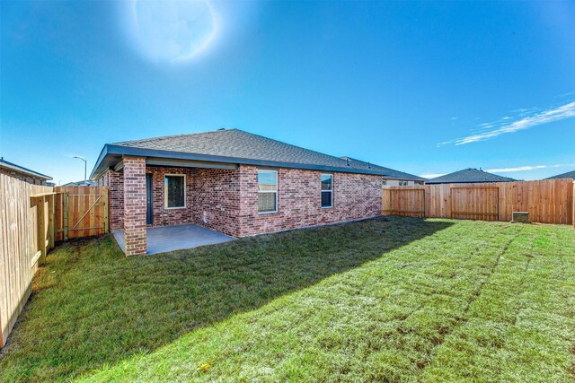 back of property featuring brick siding, a fenced backyard, a patio area, and a yard