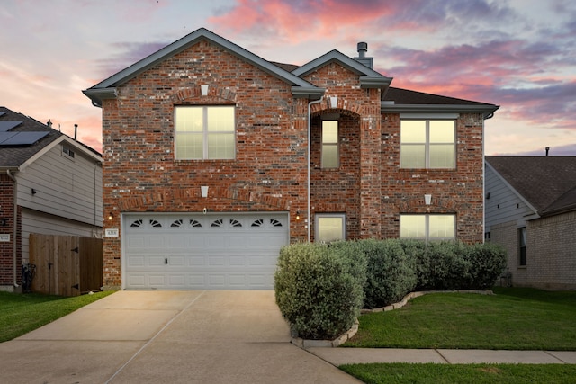 traditional-style house with a front yard, a chimney, brick siding, concrete driveway, and an attached garage