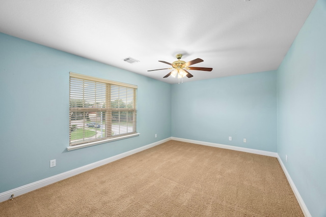 carpeted spare room featuring ceiling fan, visible vents, and baseboards