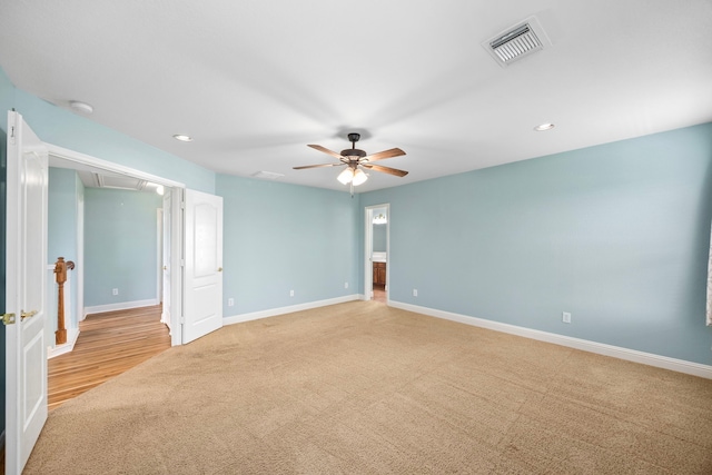 spare room with visible vents, light carpet, baseboards, attic access, and a ceiling fan