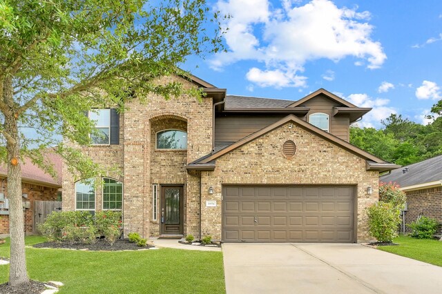 traditional home with fence, an attached garage, a front lawn, brick siding, and concrete driveway