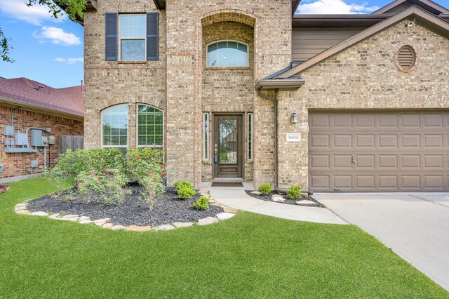 view of front of home featuring concrete driveway, brick siding, and a front yard