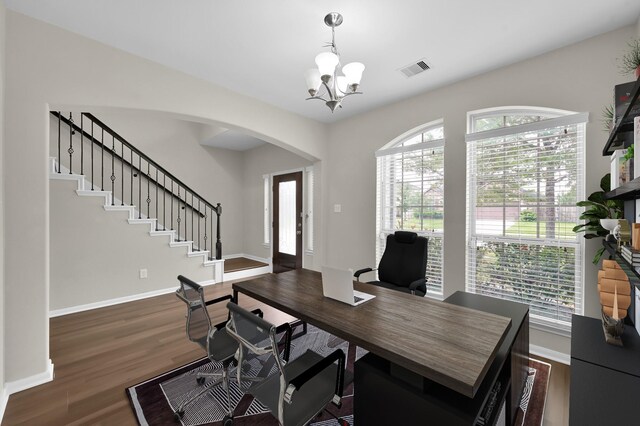 home office featuring visible vents, arched walkways, wood finished floors, and an inviting chandelier