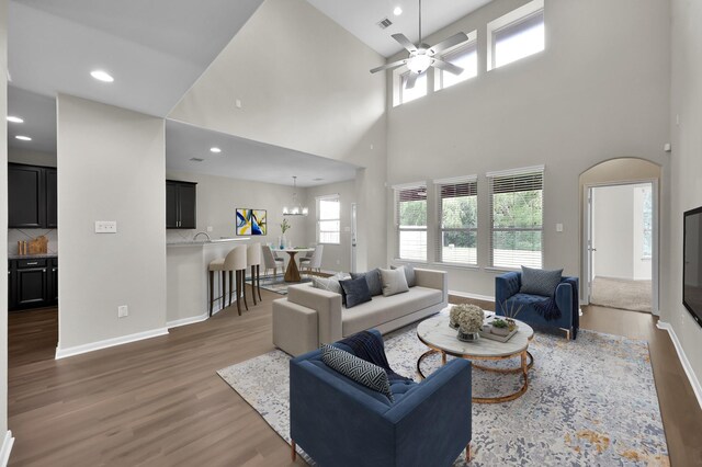 living area featuring baseboards, ceiling fan with notable chandelier, and wood finished floors