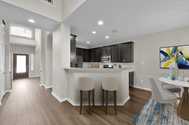 kitchen with backsplash, visible vents, appliances with stainless steel finishes, wood finished floors, and baseboards