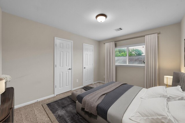 carpeted bedroom featuring baseboards and visible vents